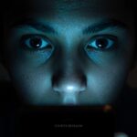 Person curiously viewing phone screen, glowing light, 'Secrets Revealed' text.