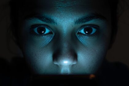 Person curiously viewing phone screen, glowing light, 'Secrets Revealed' text.