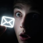 Person reacting with excitement to an interactive email screen showing a glowing button, representing Gamified Email Campaigns That Capture Attention.