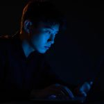 Person with a bold, expressive face illuminated by neon lights, pointing upward with confidence, symbolizing the power of a Social Media Micro-Branding Strategy.